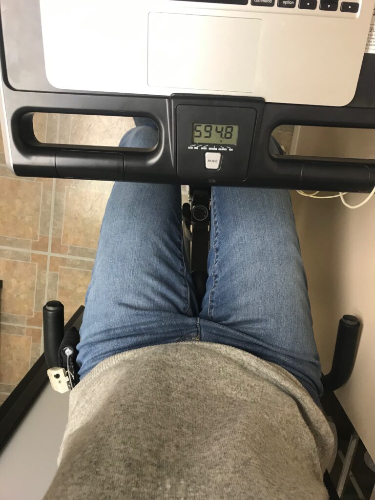 view from above of legs in jeans riding a stationary bike