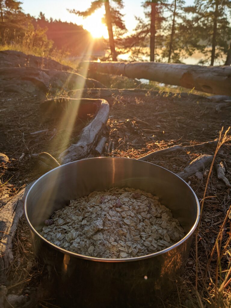oatmeal in a camping pot with sunlight coming over a lake